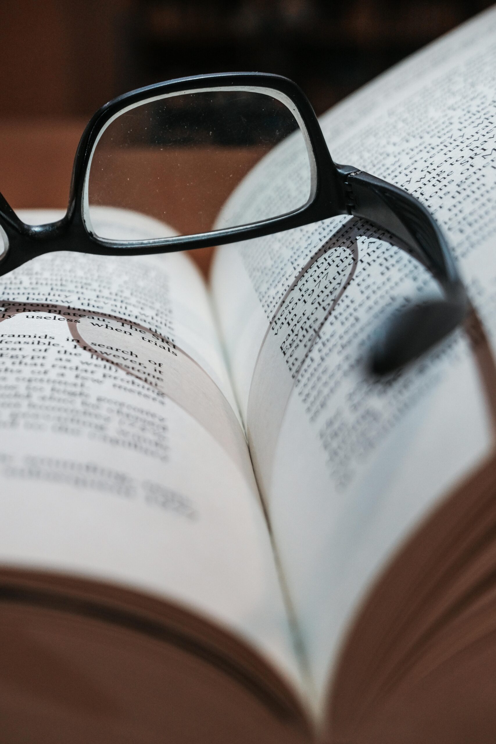 Eyeglasses resting on an open book, highlighting focus and depth of field.